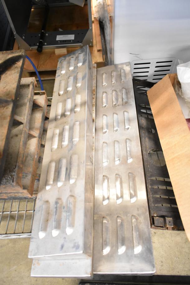 Assorted metal range grates and Turbochef kick plates in various conditions, stacked for auction.