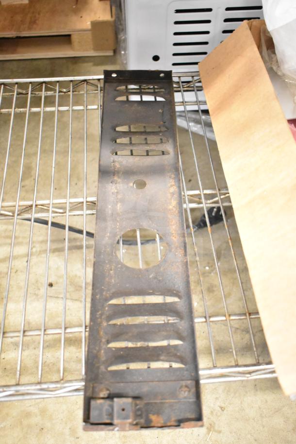 Rustic metal kick plate on wire shelf; part of a lot including range grates and Turbochef components. Some visible wear.