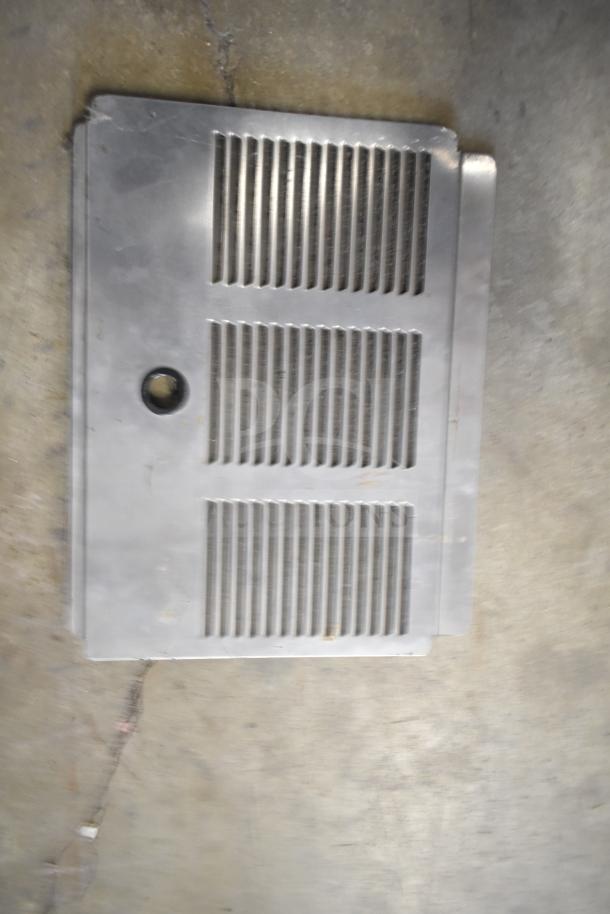 Metal plate with vertical slats and round hole, part of a lot including beverage machine hoppers and other kitchen equipment.