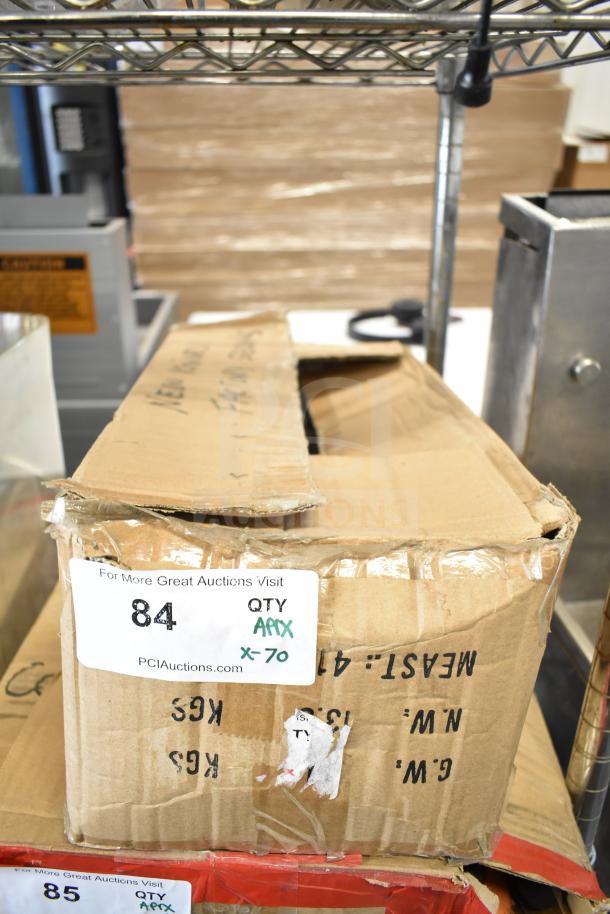 Cardboard box containing 70 sharpened stainless steel chef knives displayed on a metal shelf, labeled "QTY APPX x-70".