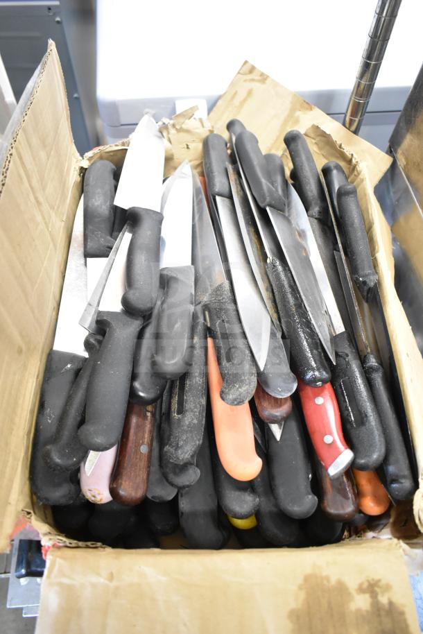Box of 75 sharpened stainless steel chef knives with assorted handles, ready for auction. Various handle colors and styles.