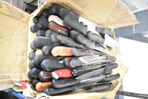 Cardboard box with 75 sharpened stainless steel chef knives, various handle colors, used condition.