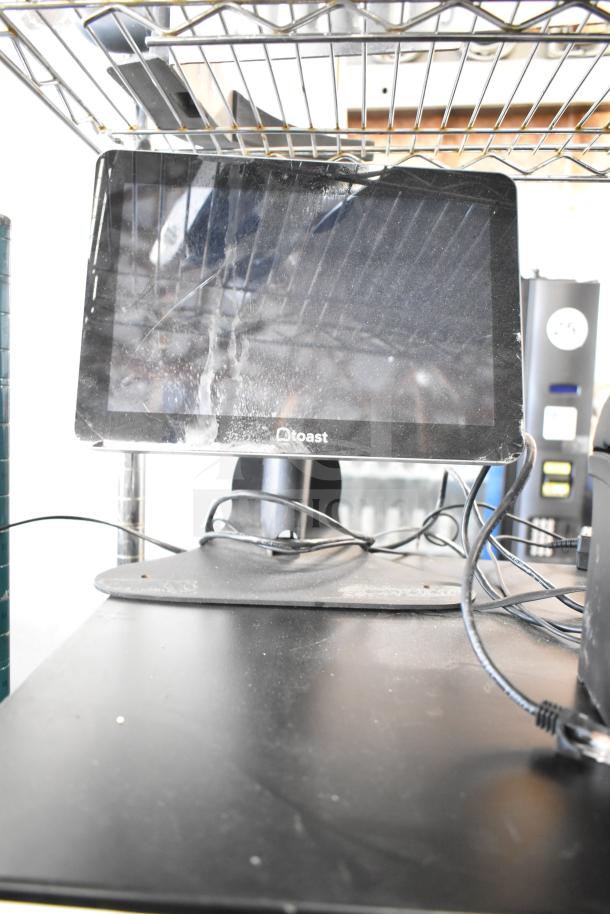 Toast POS system on counter with visible monitor, wires, and cash drawers. Used condition with minor wear.