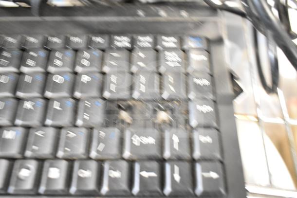 Blurry close-up of a keyboard with missing keys, part of a POS system featuring two cash drawers, a receipt printer, and a Toast monitor.