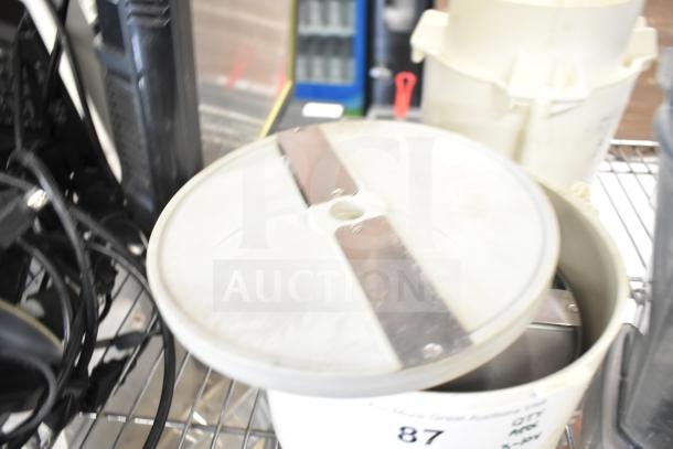 Alt text: Assorted kitchen equipment including slushie machine hoppers, slicing blade, blender pitcher, on metal shelf.