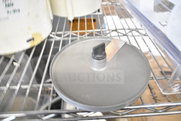 Various items including slushie machine hoppers and slicing blade on metal shelving. Moderate wear visible.