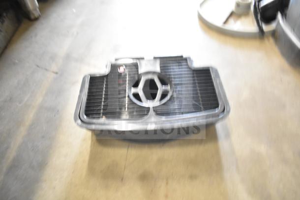 Blurry image of a metal component, possibly from slushie machine hoppers. Exact details unclear. Appears used.