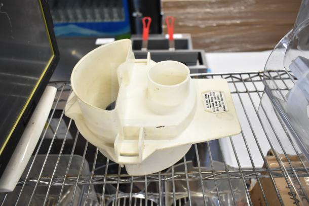 White plastic slushie machine hopper component on metal rack. Slight wear; caution label visible. Part of a mixed auction lot.