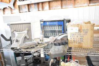 20 various kitchen equipment items including a meat slicer arm, pelican head blades, and food processor blades, on shelving.