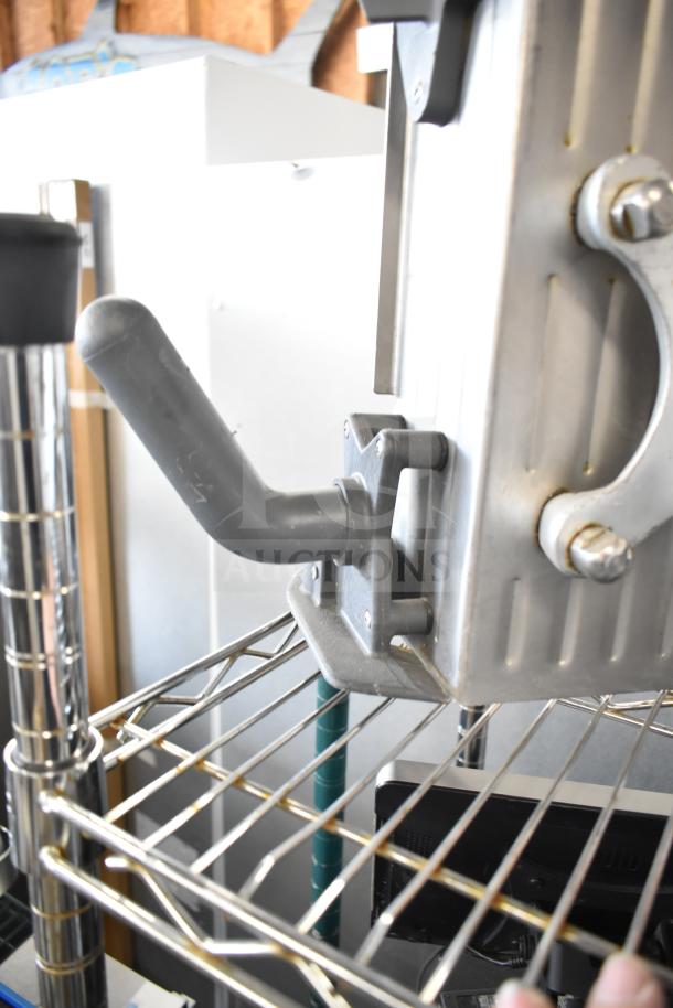 Industrial meat slicer arm mounted on metal shelving, used condition. Part of a lot with 20 food processing items.