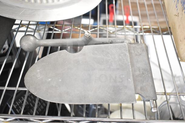 Metal meat slicer arm on a wire rack with visible blade and mounting hardware; appears in used condition.