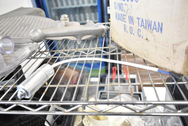 20 assorted kitchen equipment parts, including a meat slicer arm and food processor blades, on a wire shelf. Box marked "Made in Taiwan ROC."