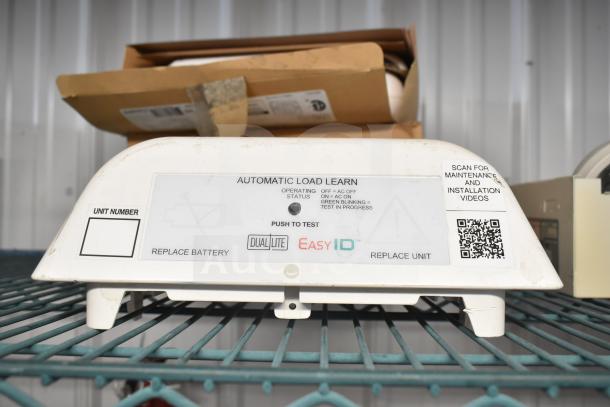 Emergency light with "Automatic Load Learn" feature by Dual-Lite. White casing with operational status markings.