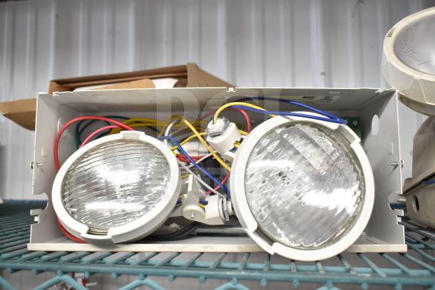 Emergency light fixture with dual round lamps, visible colored wires, in used condition on metal shelf.