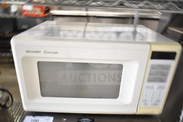 Sharp Carousel R-3A47 countertop microwave oven, beige, with control panel and viewing window. Includes plate, 120V, used condition.