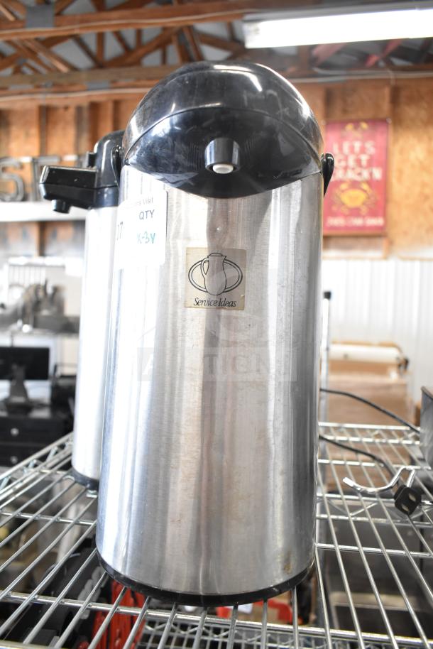 Three stainless steel air pots from Service Ideas, featuring black plastic lids and ergonomic handles. Used condition.