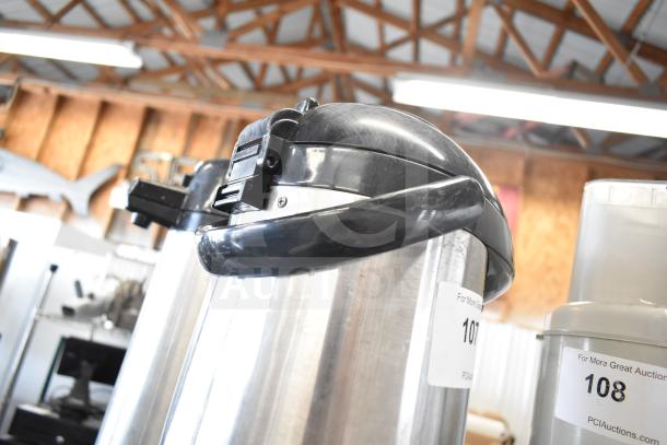 Three stainless steel air pots with black plastic lids, in used condition, labeled "107" and "108" from PCI Auctions.