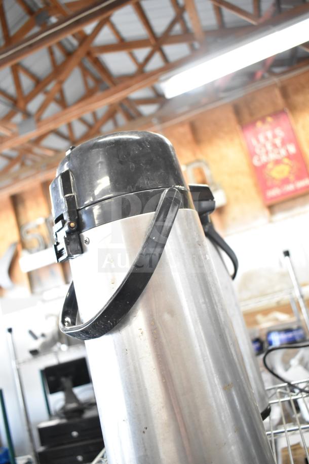 Three stainless steel air pots with black lids and handles, showing signs of wear. Used for beverage dispensing.