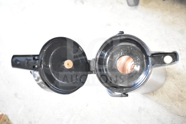 Stainless steel air pot with open lid, showing interior. Used for hot beverages. Minor wear visible.