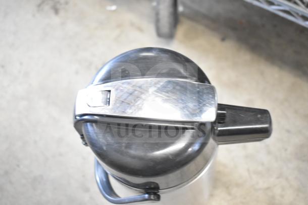 Stainless steel air pot with black lid and spout, featuring a durable handle. Suitable for beverages. Good condition.