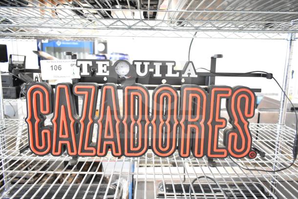 Illuminated Tequila Cazadores sign with bold red lettering, in good condition. Auction label "106" attached.