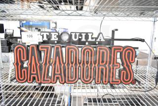 Illuminated Tequila Cazadores sign with bold red lettering, in good condition. Auction label "106" attached.