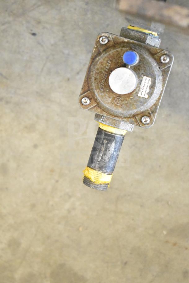 A rusty gas valve with visible wear, featuring a blue cap and label indicating pressure ratings.