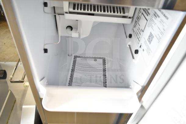 Brand new 2025 Hoshizaki AM-50BAK-DS ice machine, 115 volts, top hat cuber. Interior view shows labels and documentation.