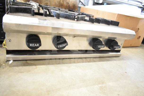 Commercial countertop gas-powered 4 burner range, stainless steel, labeled knobs for front and rear control, used condition.