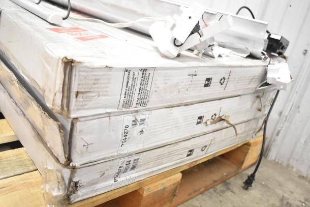 Stack of Philips PT44070 2x4 LED light panels and tube lights. Boxes show visible wear, stored on a wooden pallet.