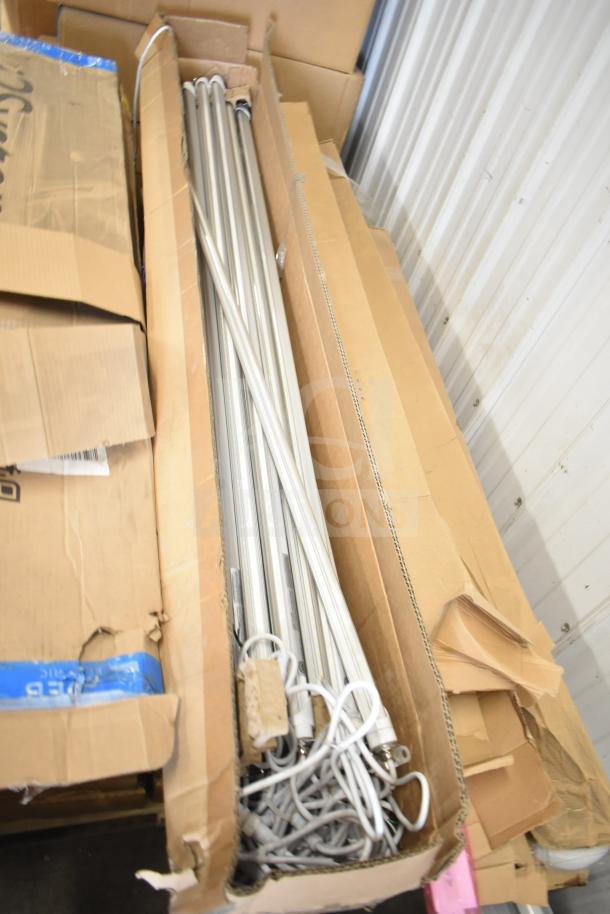 Cardboard box containing i2Systems light strips, multiple units, cords visible, packaging slightly worn, ideal for bulk purchase.