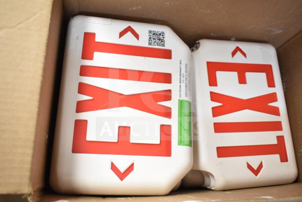 Cardboard box containing brand new DualLite exit signs with red lettering and visible labels.