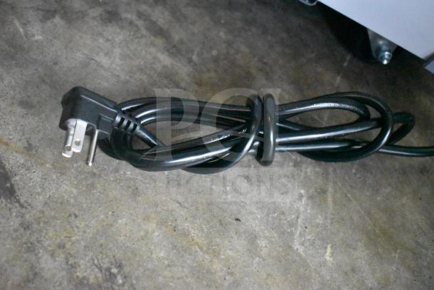 Coiled black power cord of Avantco 360DFC6HCL ice cream freezer on concrete floor. 115 Volts, 1 Phase.