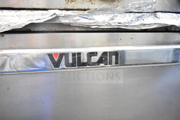 Vulcan 36S-Y1A commercial range detail showing front logo. Features 6 burners, oven, shelf, and backsplash. 215,000 BTU.