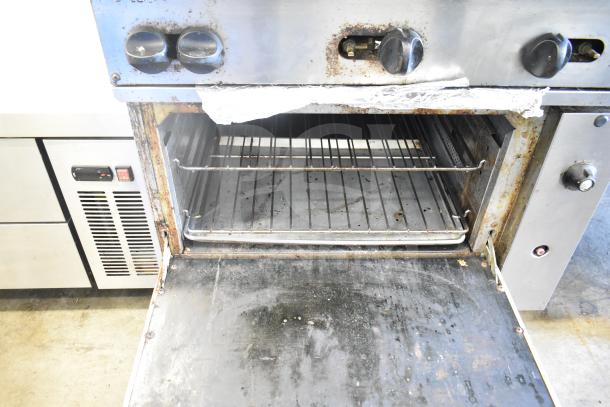 Vulcan 36S-Y1A gas range with six burners, oven, over shelf, back splash, and casters. Shows usage wear. 215,000 BTU.