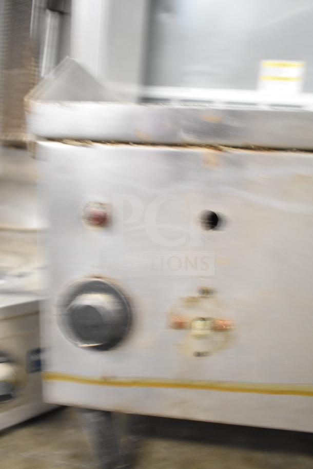 Blurred image of a countertop electric flat top griddle, showing control knobs. 208 volts, 1 phase. Some wear visible.