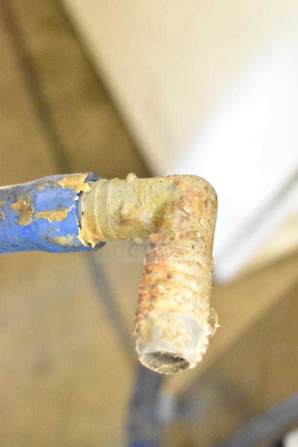 A damaged hose fitting on a commercial beverage machine with visible corrosion and wear, indicating potential maintenance needs.