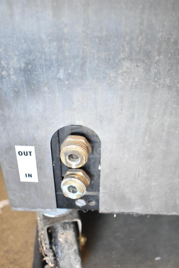 SaniServ W5273P soft serve machine connections; marked "OUT" and "IN" with visible rust on commercial casters.
