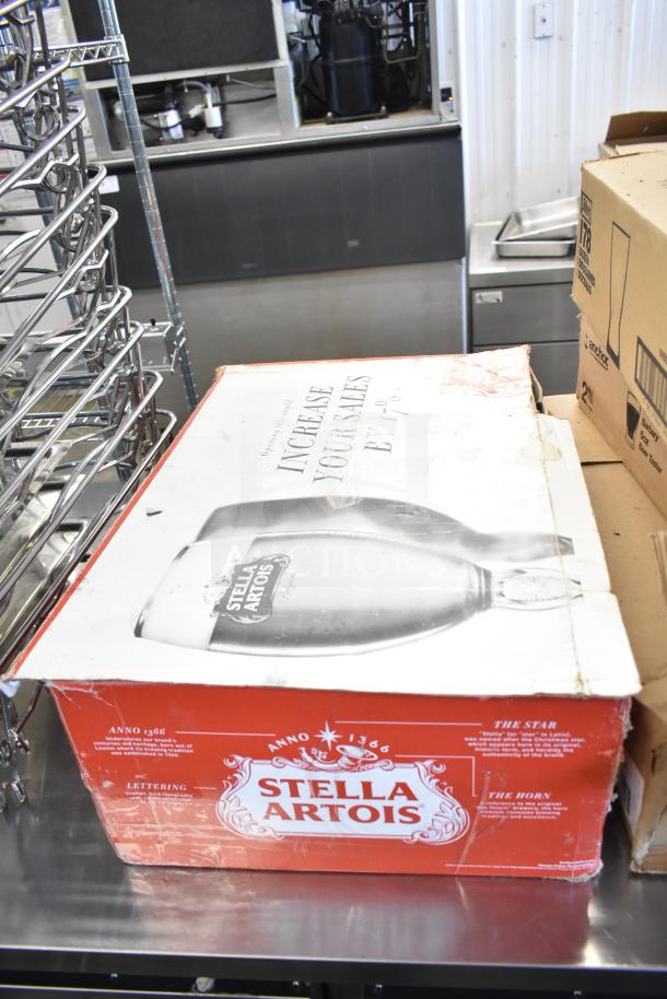 Stella Artois beer glass box on a metal surface; worn condition with brand logo and marketing text visible.