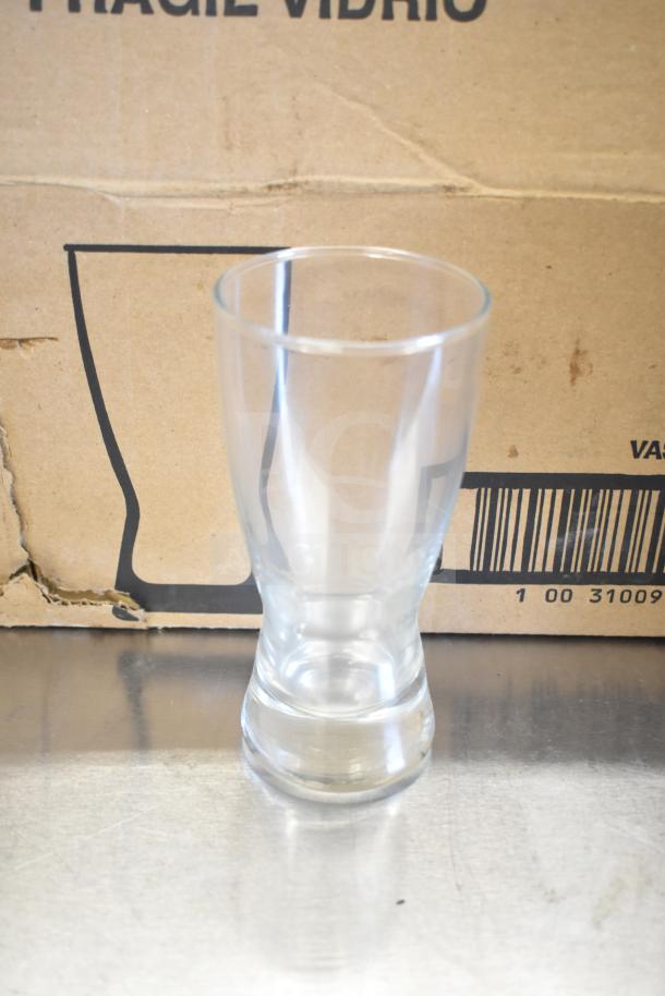 Libbey 178 Hourglass 10 oz. customizable pilsner glass, clear, on a reflective surface, cardboard box background.