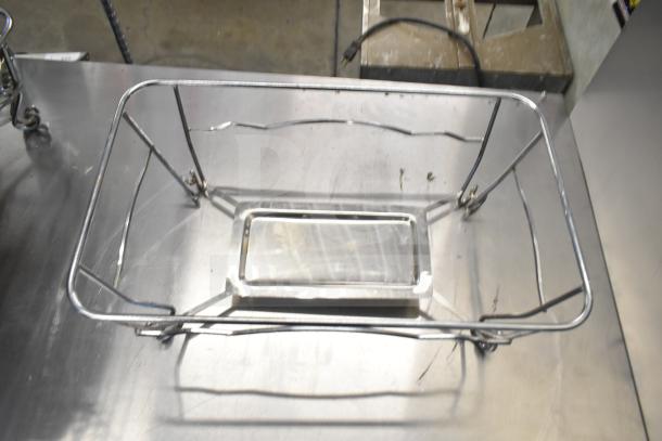 Metal chafing dish frame on stainless steel surface, showing structure and support elements. Part of 15-item auction lot.