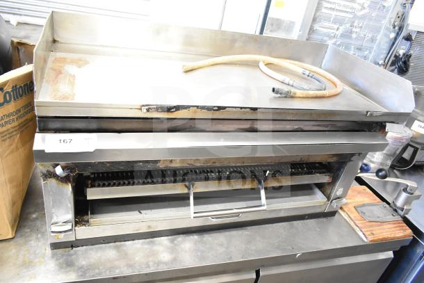 Commercial gas-powered flat top griddle with cheese melter, stainless steel, used condition, visible hose, item tag 167.
