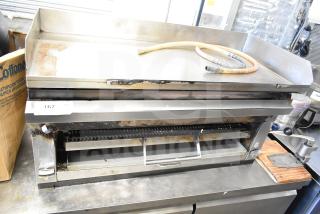 Commercial gas-powered flat top griddle with cheese melter, stainless steel, used condition, visible hose, item tag 167.