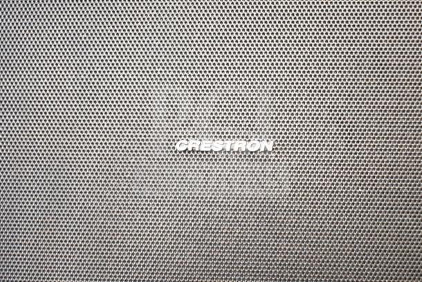 Crestron speaker with perforated metal grille, featuring Crestron logo. Part of auction lot including QSC AD-S6T speakers.
