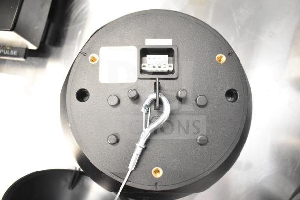 Black Crestron speaker bottom view with mounting hook, connection port, and label. Part of an 8-item auction lot.