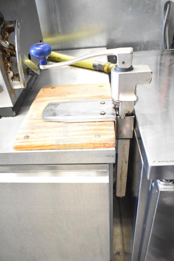 Commercial kitchen setup featuring stainless steel surfaces, cooling equipment, and a mounted rotary tool with a blue handle.