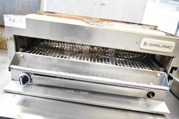 Garland commercial gas cheese melter, stainless steel, used condition, visible branding, adjustable knob, auction label present.