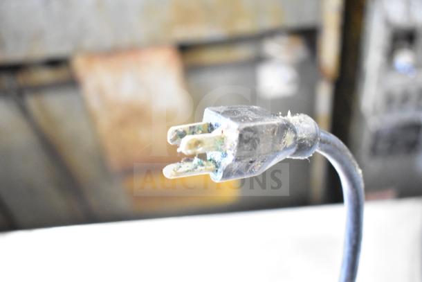 A close-up of a dirty and corroded electrical plug from a True TRCB-72 commercial chef base.