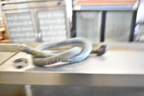 Blurry image of a commercial gas range with 6 burners, oven, over shelf, and backsplash. Condition unclear.