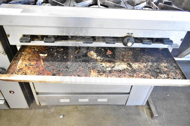 Commercial gas-powered 6-burner range with oven, overhead shelf, and backsplash. Heavy use evident; needs cleaning.